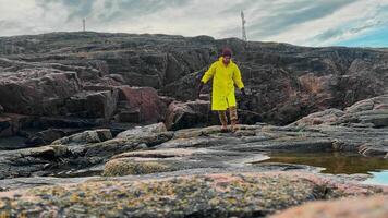 Warm, waterproof shoes and clothing help hiker enjoy walk on wet stones after rain without any problems. Tourist in bright clothes, enjoying beautiful northern nature and exploring rocky terrain. video