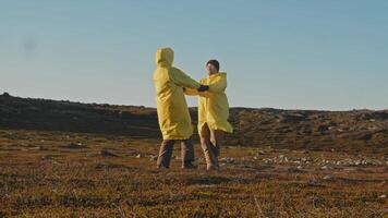 Couple of lovers in middle of northern landscape, surrounded by tundra, are spinning and playing around, then kissing and hugging each other. travelers in lands beyond Arctic Circle video