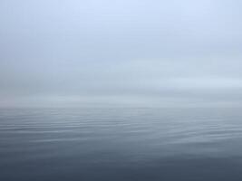 thick white fog fell on the sea, calm and silence, the water merges with the sky photo