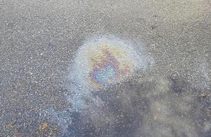 A rainbow spot of gasoline on the asphalt on a rainy summer day photo