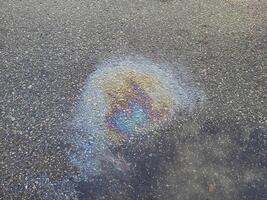 A rainbow spot of gasoline on the asphalt is a donkey of rain on a summer day. photo