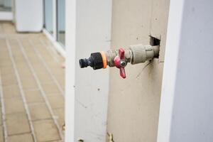 Building fire hydrants on the wall of a building. A water tap sticks out of the wall in the street. photo