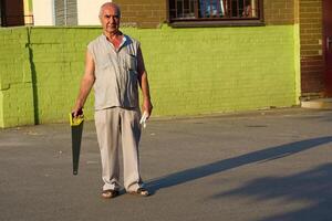 Elderly smiling man carpenter with saw in summer clothes photo