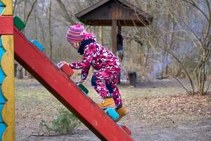 Cute child playing on the ladder at the playground photo