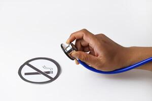 A persons hand holding a Stethoscope examining paper in the smoking ban photo