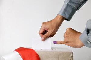 The hand inserts the voting paper into the ballot box made of cardboard photo