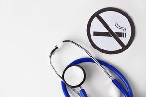 Stethoscope and round paper cutout having no smoking symbol on white background photo