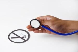 Person's hand using a stethoscope to analyze smoking ban document photo