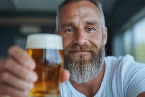 Close up portrait of handsome bearded man drinking beer. He is looking at camera and smiling photo