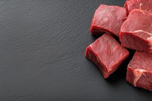 Raw beef meat on black slate background. Top view with copy space photo