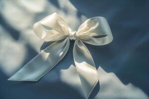 close-up white silk ribbon tied into a bow on gray surface top view with bright sunlight photo