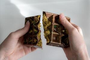 Trend Dubai chocolate with pistachio, tahini and kataifi dough, chocolate broken in woman's hands. Handmade confectionary photo