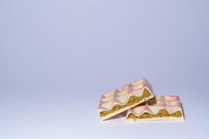 Famous white Dubai chocolate with pistachio, dried raspberry, tahini and kadaif, on white background with copy space, isolated, showing the filling. Confectionery and handmade sweets, chocolatier photo