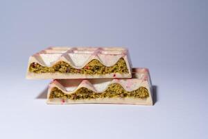Popular white Dubai chocolate with pistachio, dried raspberry, tahini and kadaif, on white background, isolated, showing the filling. Confectionery and handmade sweets, chocolatier photo