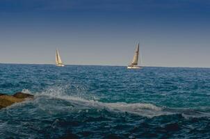 Serene Ocean View with two Sailboats and Crashing Waves background photo
