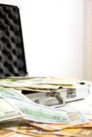 A silver case is open, spilling out US dollar bills photo