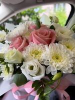 Fresh pink roses and white chrysanthemums arranged elegantly inside a car, capturing a moment of joy and beauty photo