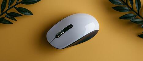 White wireless computer mouse on yellow background with dark green leaves photo