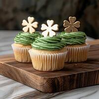 Three St Patricks Day cupcakes with green frosting and gold shamrock toppers photo