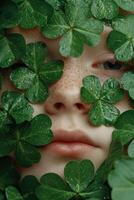 Close up of a freckled face partially covered by lush green clover leaves photo