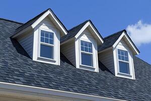 Three dormer windows on a dark gray asphalt shingle roof photo