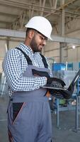 Indian operator with laptop monitors process of packing pvc profiles on production line window factory video