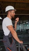 Engineer with walkie talkie giving commands to workers in PVC window factory video