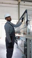 Indian engineer sets up a production line at programmable CNC machine in window factory video