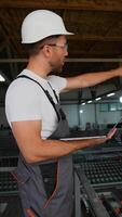 Foreman with laptop and walkie talkie giving commands to workers in PVC window factory video