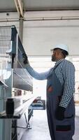 Indian Asian engineer sets up a production line at programmable CNC machine in window factory video