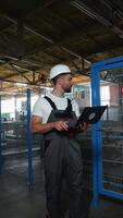 Industrial worker programmer sets up production line conveyor with laptop video