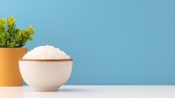 Bowl of rice beside a yellow pot with a plant on a blue background. photo