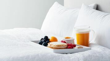 Breakfast tray on a bed with fruits, pastries, and juice. photo