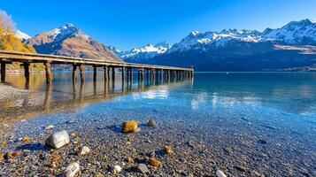 Scenic lake view with a wooden pier and snow-capped mountains in the background. photo