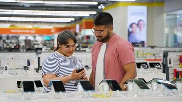 Indian couple choosing smartphone in home appliance store on Black Friday video