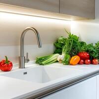 Fresh vegetables arranged by a modern kitchen sink with stylish faucet. photo