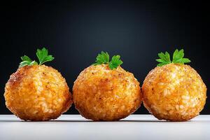 Crispy golden balls garnished with herbs on a dark background. photo
