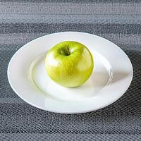 Green apple on a white plate against a textured background. photo