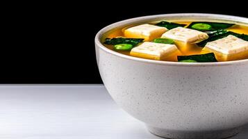 Warm tofu soup in a white bowl with greens and cubes of tofu. photo