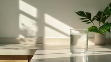 Plastic free campaign. Glass of water on a countertop with a green plant in the background. photo