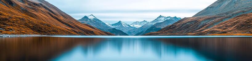 Care for freshwater ecosystem concept. Serene lake reflecting mountains and autumn foliage under a cloudy sky. photo