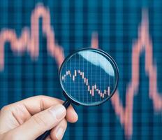 Trading strategy tip concept. Analyzing stock market trends with a magnifying glass. photo