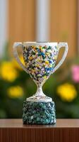 Sustainable goal achievement concept. Colorful trophy on display with floral background. photo