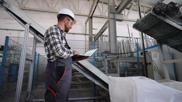 Caucasian engineer examining document using laptop at windows factory video