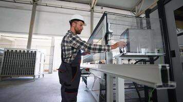 Engineer sets up a production line at programmable CNC machine in window factory video