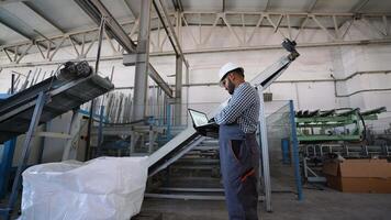 Indian engineer examining document using laptop at windows factory video