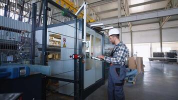 Engineer sets up a production line at programmable CNC machine in window factory video