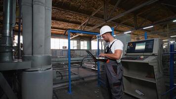 Industrial worker programmer sets up production line conveyor with laptop video