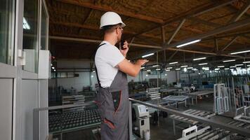 Engineer with walkie talkie giving commands to workers in PVC window factory video