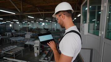 fönster fabrik chef ingenjör är använder sig av en bärbar dator med ett teknik programvara på produktion linje video